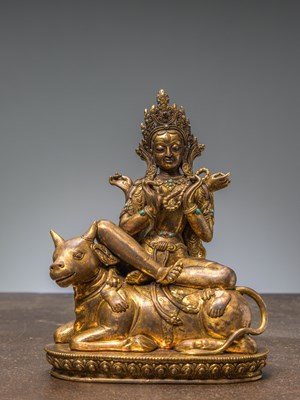 Lot 246 - A SEATED MARICI ON BULL, BRONZE GILT, TIBET 19TH CENTURY, WITH INSCRIPTION